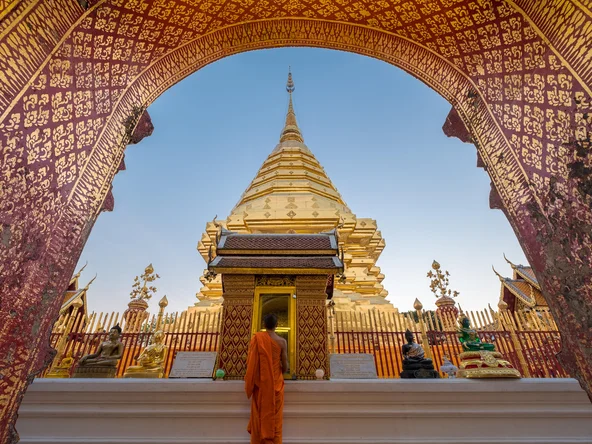 Girl looking up at gilded arch in front of golden temple in Chiang Mai 