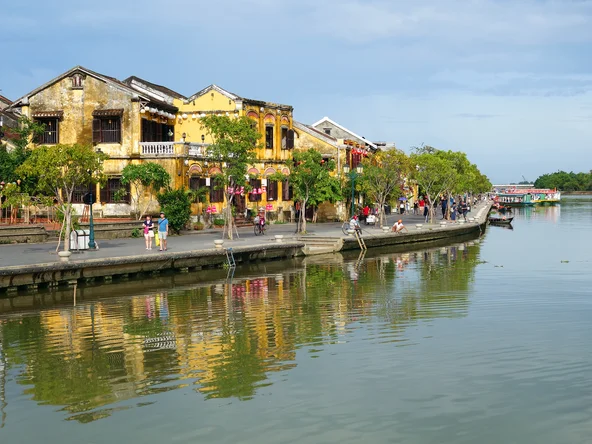 Tourists walk in Hoi An's riverside promenade during the day in Vietnam