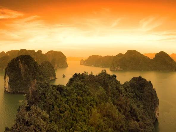 Sun sets over the dramatic limestone karst formations of Halong Bay in Vietnam