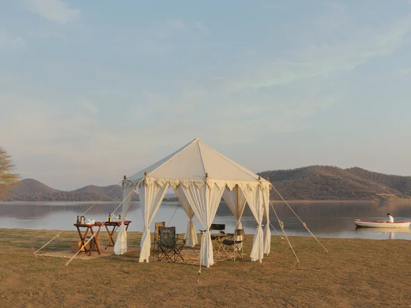 A tent with a dinner table set up by the water on a private safari experience in India in November