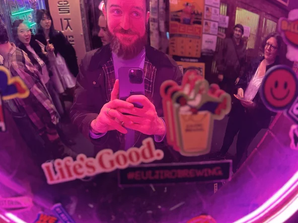 A tourist in the Euljiro Neon street in South Korea taking a selfie in a reflective surface on a Korean Wave itinerary