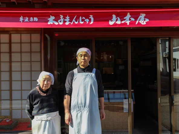 A mother and son stood in front of their family sweet shop in Japan