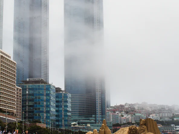 View of Busan beach with sand sculptures with the mist concealing high rise buildings