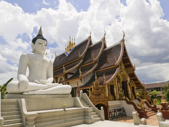 White buddha statue next to traditional golden temple in Chiang Mai