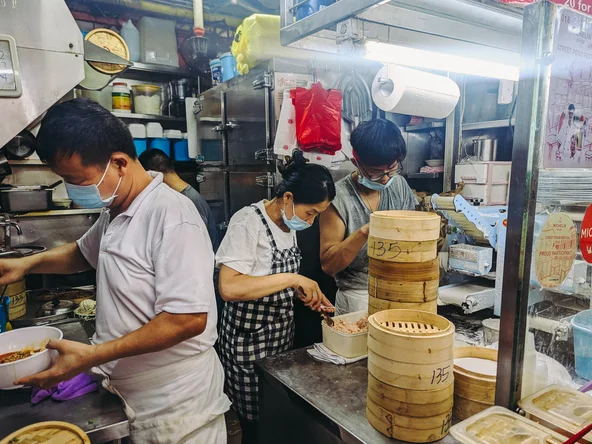 People making dumplings in a hawker market in China town Singapore