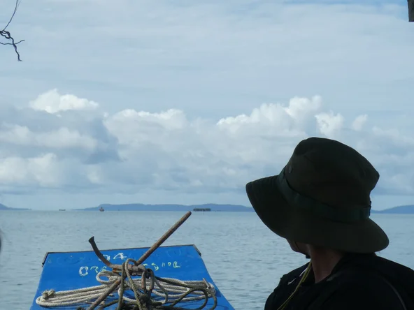 A man looks out to sea over the prow of a small wooden boat