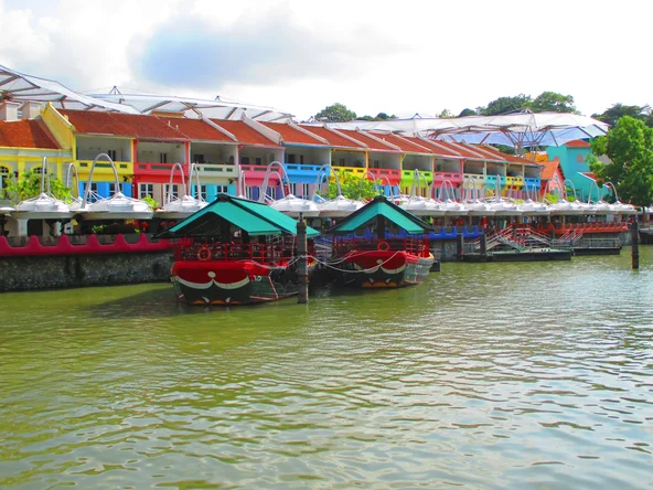 Two boats moored in front of a row of colourful shophouses