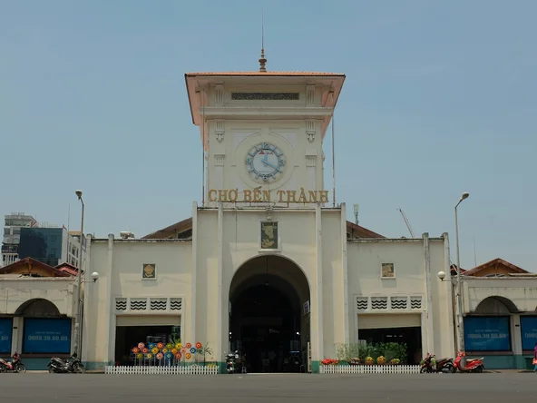 The front of Ben Thanh Market - a pale yellow building with large front entrance and windows either side