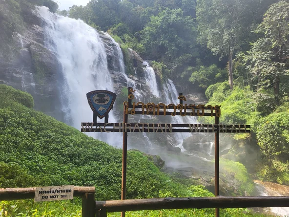 A waterfall with a wooden sign in front of it