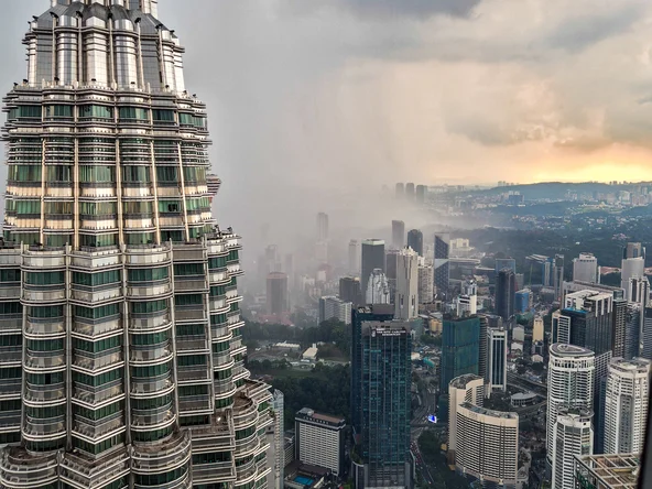 A storm cloud sits behind a skyscraper, with a cityscape in the background