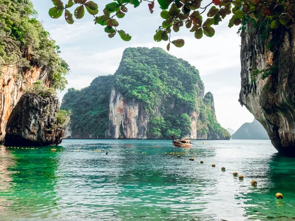 Sea view with limestone karsts in the water and a small wooden boat with a roof in the middle