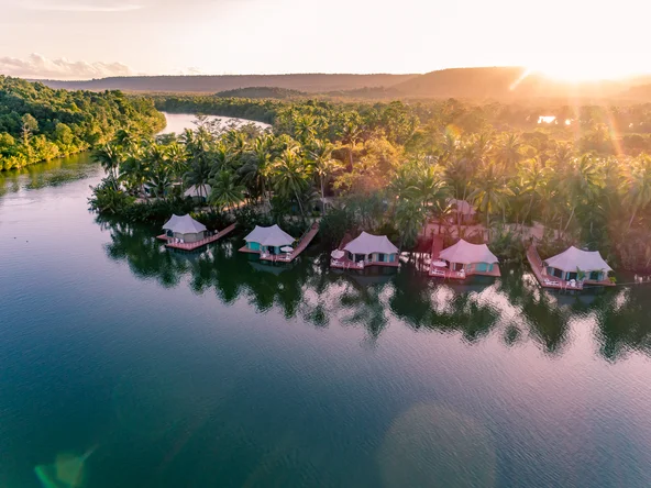 Floating tents on a river at sunset