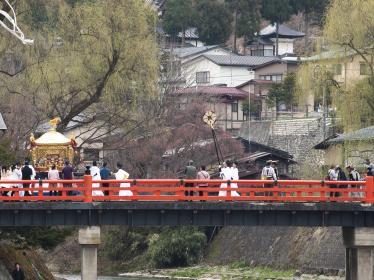 Procession of people in traditional garb over bridge in the centre of Takayama