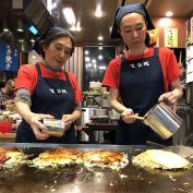 Two people preparing okonomiyaki in Hiroshima 