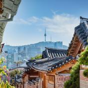 View down a street in Bukchon Hanok Village with Seoul skyline in the background