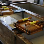 Wooden paper-making equipment sitting next to sink of water