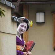 Geisha looking around corner and smiling at the camera 