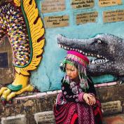 Girl in traditional dress sat in front of street art mural in Chiang Mai