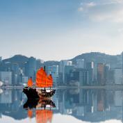 Junk boat with red flags crossing Hong Kong harbour 