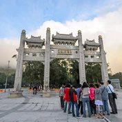 Group of people gathered in front of ornate entrance gate to Po Lin Monastery
