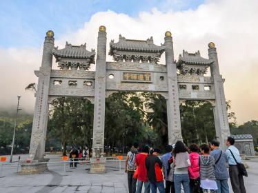 Group of people gathered in front of ornate entrance gate to Po Lin Monastery