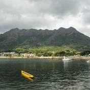 Yellow kayak in sea in front of beach and mountains in New Territories 