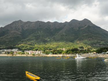 Yellow kayak in sea in front of beach and mountains in New Territories