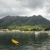 Yellow kayak in sea in front of beach and mountains in New Territories