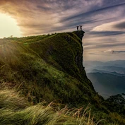 Two people on overhanging cliff in Northern Thailand at sunset 