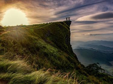 Two people on overhanging cliff in Northern Thailand at sunset