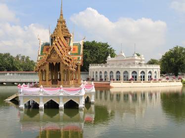 Ornate pagoda on island in middle of water with white temple in background