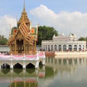 Ornate pagoda on island in middle of water with white temple in background