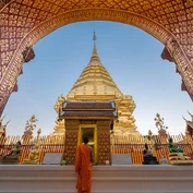 Girl looking up at gilded arch in front of golden temple in Chiang Mai 