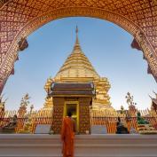 Girl looking up at gilded arch in front of golden temple in Chiang Mai 