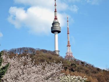 Two buildings protrude from side of a mountain against the sky in Namsan, Seoul, during spring
