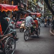 Cyclo riders weaving through busy streets of Ho Chi Minh City