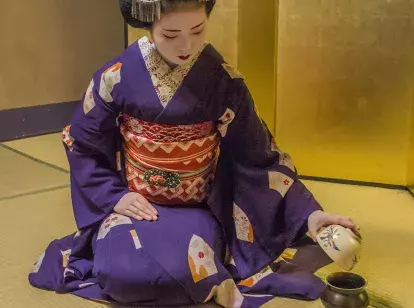 Japanese Geisha in traditional dress preparing tea for guests in Kyoto