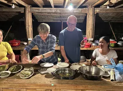 Tourist couple making dinner with Laos family at homestay
