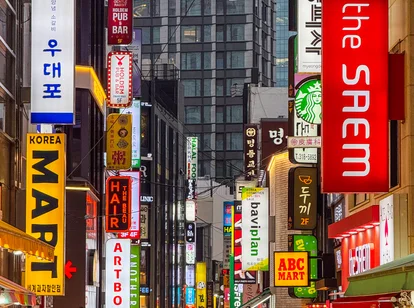 A colourful street in South Korea filled with people and bright shop signs