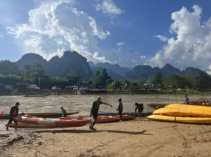 Laos Vang Vieng men collecting boats on the river
