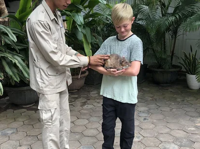 A young boy holding one of the rats at APOPO in Siem Reap with a guide on a family holiday to Cambodia