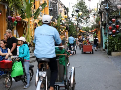 A man cycling through a lantern lined street in Hanoi