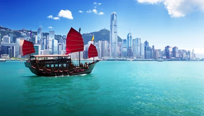 Junk boat with red flags crossing Hong Kong harbour 