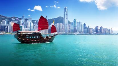 Junk boat with red flags crossing Hong Kong harbour 