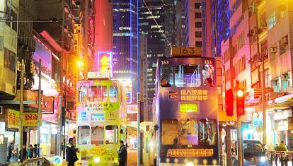 Trams at night lit up by neon signs 