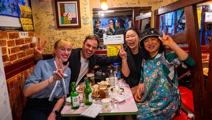 A group of people posing with peace signs at a table filled with food and drinks