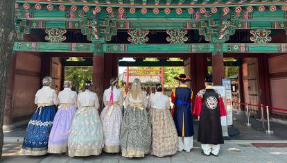 A group of people in traditional Korean hanbok attire outside an ornate gate in Jeonju