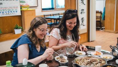 Two women enjoying authentic Korean food on a small group tour
