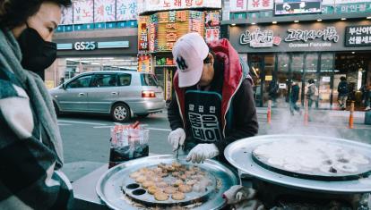 Man preparing street food on bustling South Korean street