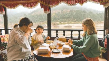 Family enjoying homecooked food on boat in Mekong Delta